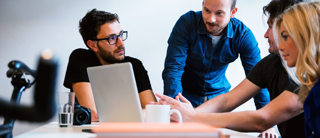 Un equipo de trabajo discute un proyecto al rededor de una computadora 