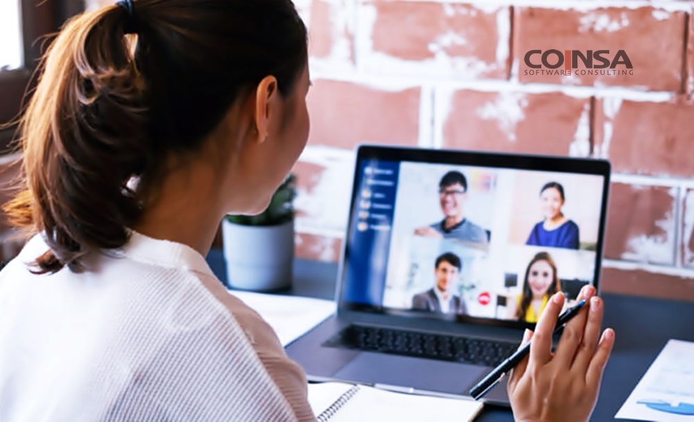 Una mujer con coleta, observa una videoconferencia tomando notas en una libreta 